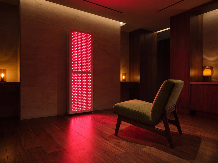 Full-body red light therapy panel glowing in a private recovery room